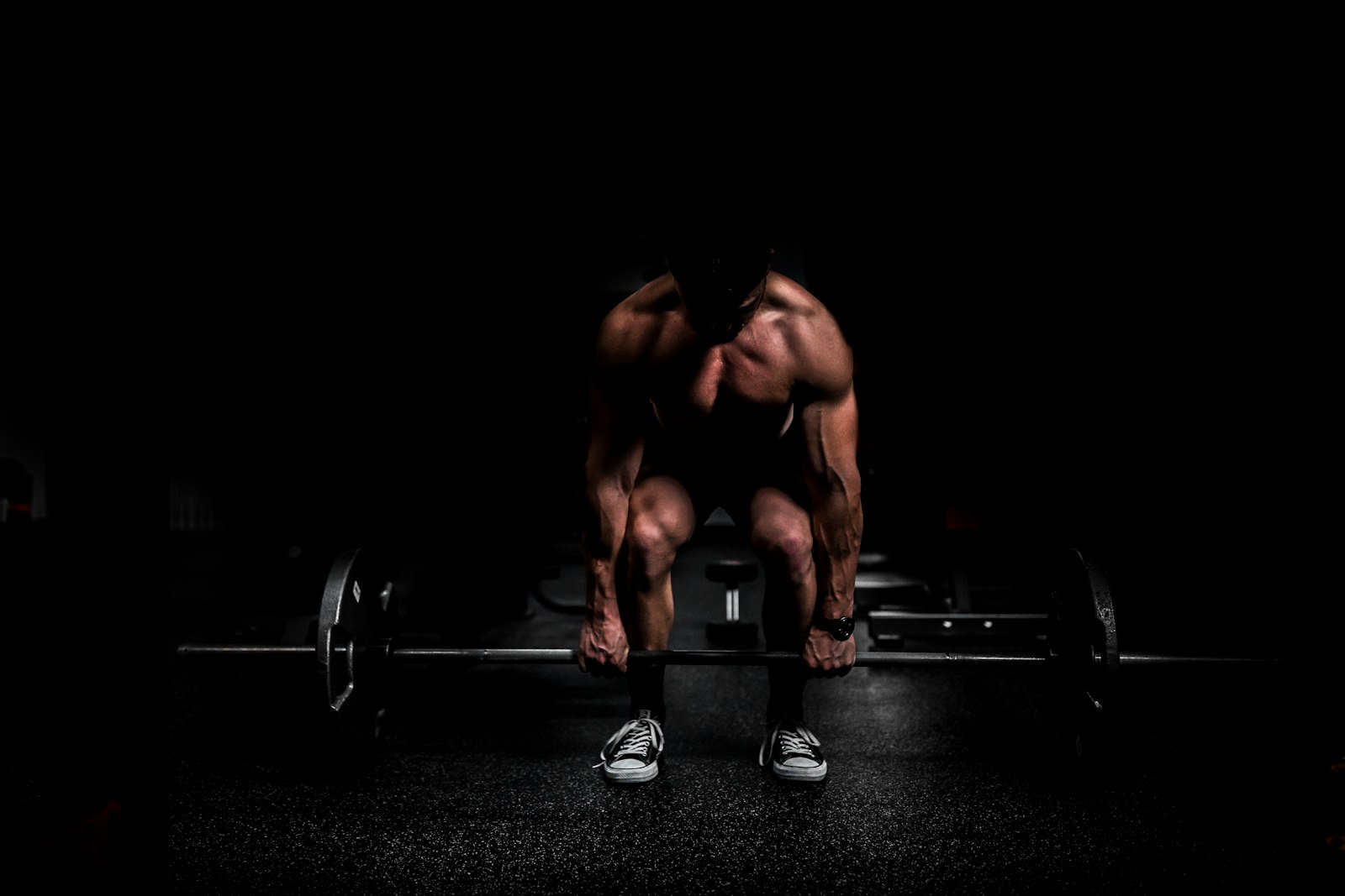 Sportiv pregătindu-se pentru un deadlift greu, într-o sală de forță slab luminată